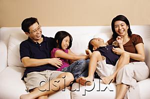 AsiaPix - Family of four on sofa, sister tickling brother