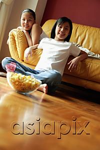 AsiaPix - Two sisters sitting in living room, looking at camera