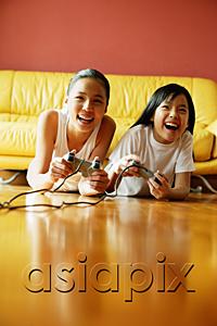 AsiaPix - Two sisters lying on floor playing video games, smiling