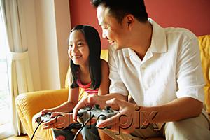 AsiaPix - Father and daughter sitting side by side playing video games