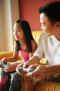AsiaPix - Father and daughter playing video games, father looking at daughter