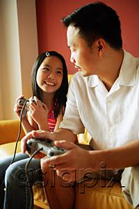 AsiaPix - Father and daughter looking at each other, holding video game controllers