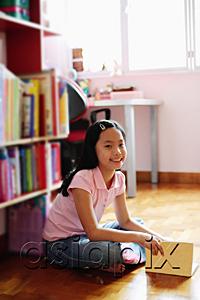 AsiaPix - Girl sitting cross-legged on floor, holding book, looking at camera