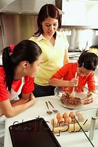AsiaPix - Mother and two daughters in kitchen, one daughter holding spoon and bowl