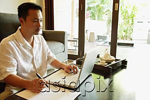 AsiaPix - Man in living room, using laptop