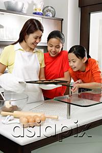 AsiaPix - Mother and two daughters in kitchen, looking at tray of cookies
