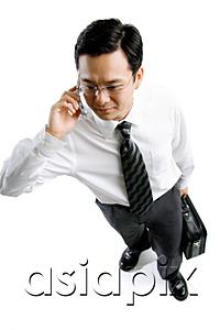 AsiaPix - Businessman carrying briefcase and using mobile phone