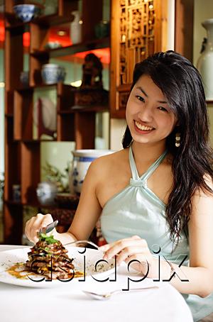 AsiaPix - Woman at restaurant, sitting at table with food, looking at camera