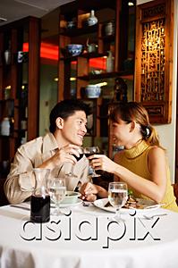 AsiaPix - Couple sitting face to face in Chinese restaurant, toasting with wine glasses