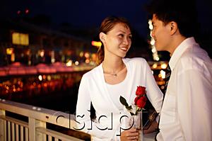 AsiaPix - Couple standing face to face, woman holding single rose stalk
