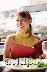 AsiaPix - Woman in cafe, holding menu, looking away
