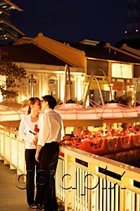 AsiaPix - Couple kissing on bridge, woman holding roses