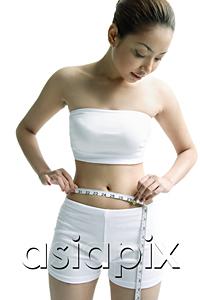 AsiaPix - Young woman measuring her waist with measuring tape