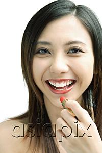 AsiaPix - Woman smiling at camera, putting on lipstick