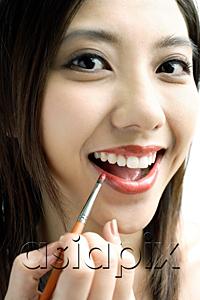 AsiaPix - Woman smiling at camera, putting on lipstick with lip brush