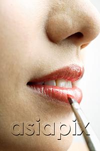 AsiaPix - Close up of woman's mouth, putting on lipstick with lip brush