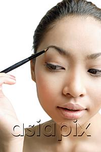 AsiaPix - Young woman holding eyebrow pencil to eyebrow