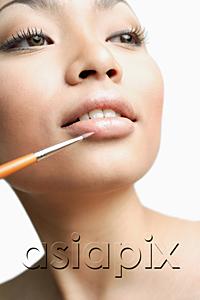 AsiaPix - Woman using lipstick brush, portrait