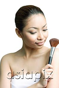 AsiaPix - Woman holding make-up brush, looking away