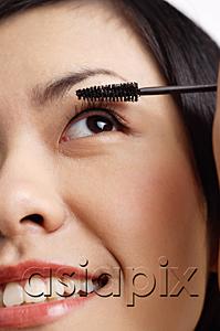 AsiaPix - Woman applying mascara, close-up of face