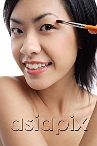 AsiaPix - Woman holding brush, applying eyeshadow