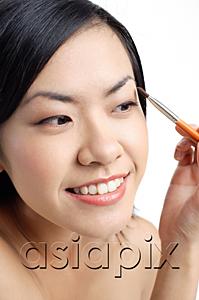 AsiaPix - Woman holding brush, applying eyeshadow, looking away