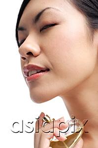 AsiaPix - Woman holding perfume bottle, spraying on neck, eyes closed