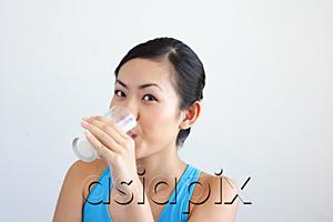 AsiaPix - Woman drinking glass of milk, looking at camera