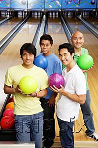 AsiaPix - Four men standing in bowling alley, holding bowling balls