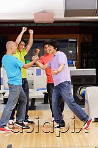 AsiaPix - Four guys at a bowling alley, arms raised in victory