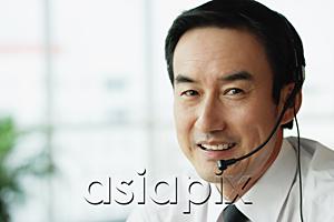 AsiaPix - Businessman looking at camera, wearing headset
