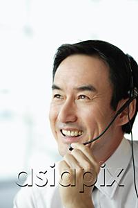 AsiaPix - Businessman using headset, smiling, looking away