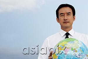 AsiaPix - Businessman holding globe, looking away