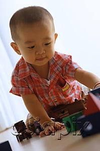 AsiaPix - Young boy on floor, playing with toy train