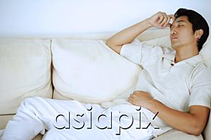 AsiaPix - Man lying on sofa, sleeping, hand on head