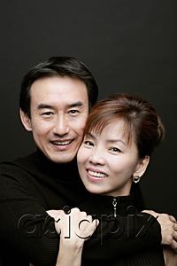 AsiaPix - Couple looking at camera, man with arm around woman