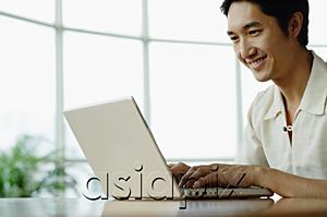 AsiaPix - Man sitting, using laptop, smiling
