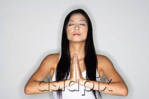 AsiaPix - Woman practicing yoga, hands together, eyes closed