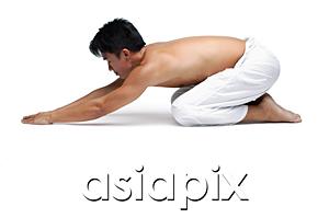 AsiaPix - Man kneeling on floor in yoga position