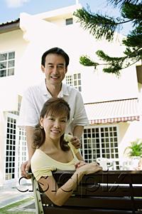 AsiaPix - Mature couple looking at camera smiling, husband standing behind wife
