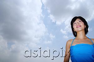 AsiaPix - Young woman standing, looking away, low angle view