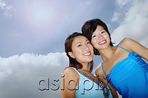AsiaPix - Two women standing cheek to cheek, smiling at camera, low angle view