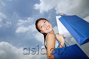 AsiaPix - Young woman with shopping bags, smiling at camera, low angle view