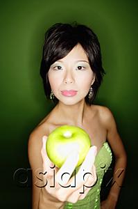 AsiaPix - Woman in green dress, holding green apple towards camera