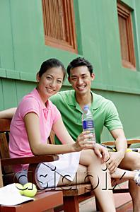 AsiaPix - Man and woman sitting on bench, smiling at camera, woman with water bottle