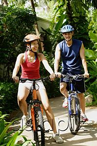 AsiaPix - Couple wearing helmets, riding bikes, smiling