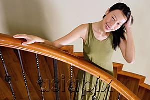 AsiaPix - Woman standing on staircase, hand on head, smiling