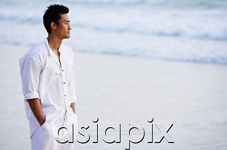 AsiaPix - Man standing on beach, hands in pocket, looking away