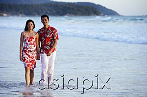 AsiaPix - Couple walking on beach, ankle deep in water, holding hands, smiling at camera