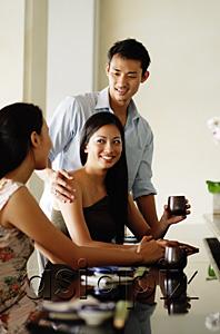 AsiaPix - Young adults in restaurant, women sitting, man standing next to woman